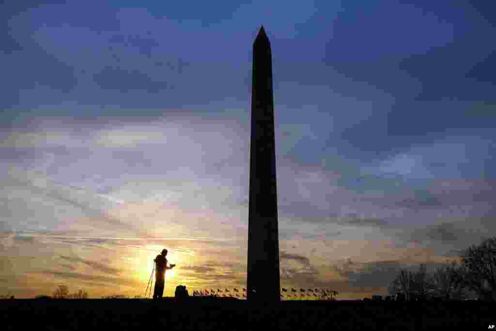 Silhouetted in the setting sun, a photographer works with his camera in the shadow of the Washington Monument in Washington, D.C., Feb. 21, 2017.