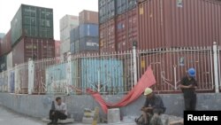 Laborers rest next to containers outside a logistics center near Tianjin Port, in northern China, May 16, 2019.