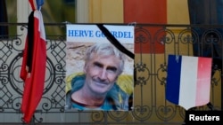 A portrait of mountain guide Frenchman Herve Gourdel hangs near a French flag outside the town hall in Saint-Martin-Vesubie, Sept. 25, 2014.