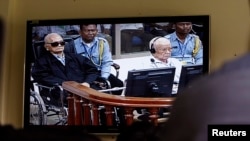 FILE - Khieu Samphan, second from right, former Khmer Rouge head of state, and Noun Chea, left, who was the Khmer Rouge's chief ideologist and No. 2 leader, are seen on a screen at the court's press center of the U.N.-backed war crimes tribunal in Phnom Penh, Cambodia, Aug. 7, 2014. 