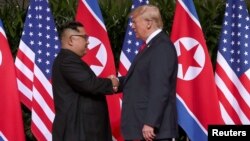 Presiden AS Donald Trump (kanan) dan pemimpin Korea Utara Kim Jong-un berjabat tangan hari Selasa (12/6) pagi di Singapura.