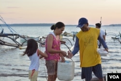 The wife and daughter of fisherman Junick Josol help him prepare for a routine overnight fishing trip some 24 kilometers from the shores of Masinloc town on the South China Sea, Masinloc, Philippines, Nov. 8, 2015. (S. Orendain/VOA)