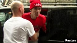 Canadian pop star Justin Bieber is held back by a member of his security team as he confronts a photographer outside his hotel in central London, March 8, 2013.