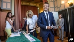 French President Emmanuel Macron and his wife Brigitte Macron pick up ballots before voting in the first round of the two-stage legislative elections in Le Touquet, northern France, June 11, 2017.