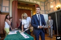 French President Emmanuel Macron and his wife Brigitte Macron pick up ballots before voting in the first round of the two-stage legislative elections in Le Touquet, northern France, June 11, 2017.