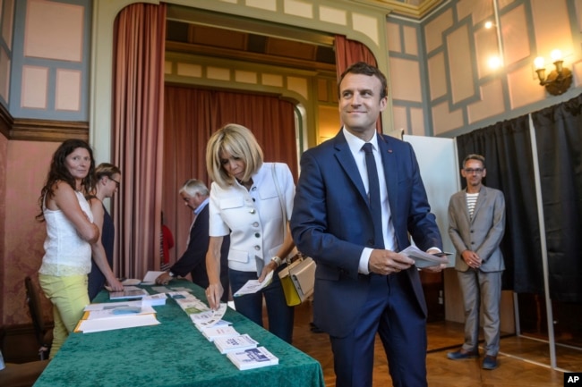 French President Emmanuel Macron and his wife Brigitte Macron pick up ballots before voting in the first round of the two-stage legislative elections in Le Touquet, northern France, June 11, 2017.