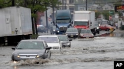 FILE - Vehicles drive on floodwaters, May 5, 2017, in Newark, N.J. Heavy rains caused flooding in New York City and flight delays in the region.