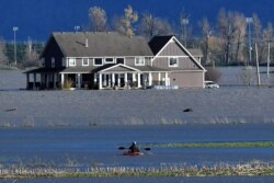 A paddler kayaks on a flooded stretch of farmland in Abbotsford, British Columbia, Canada, November 16, 2021.