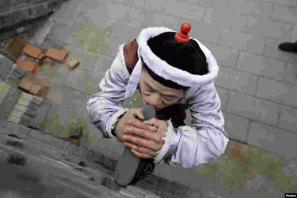 Một nghệ sĩ dân gian vận động tay chân trong lúc chờ đợi đến phiên biểu diễn tại lễ hội Mùa Xuân ở công viên Long Đàm, Bắc Kinh trong ngày mùng 5 âm lịch.