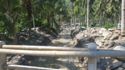 Alat berat ekskavator membersihkan aliran sungai mati di desa Poi yang dipenuhi material pasir bercampur batu-batu besar yang terbawa banjir bandang, 9 Desember 2019. (Foto: Yoanes Litha/VOA)