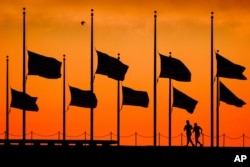 Runners pass under the the flags flying at half-staff around the Washington Monument at daybreak in Washington, Monday, June 13, 2016. The flags were ordered to half-staff by President Barack Obama to honor the victims of the Orlando nightclub shootings.