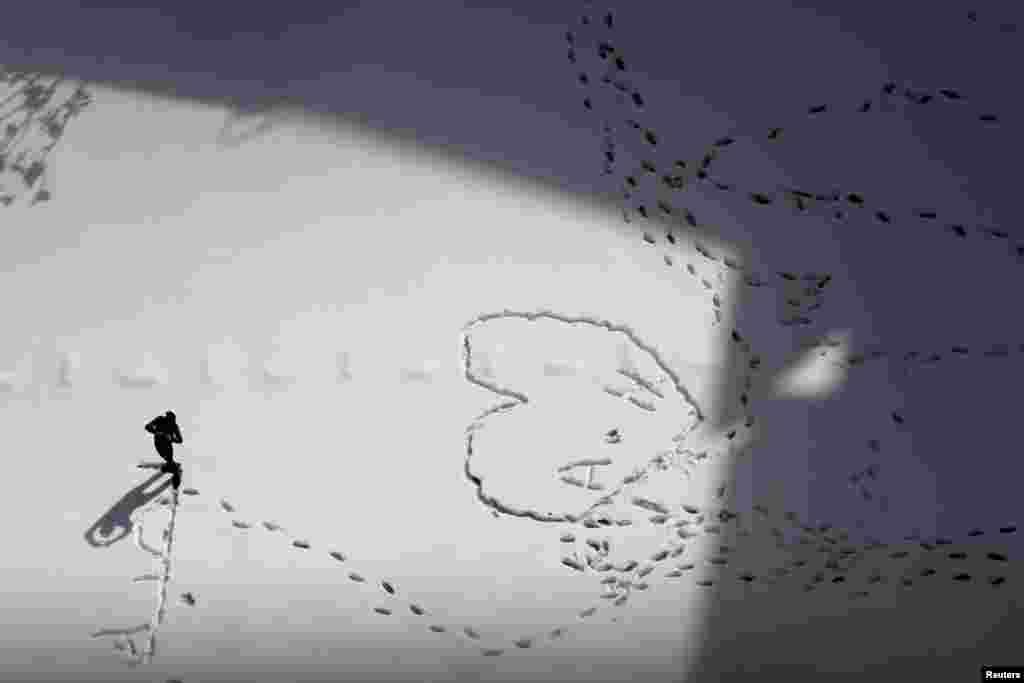 A man makes patterns in the snow during a heavy snowstorm in Amman, Jordan.