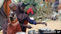 A Somali woman cooks food for her children in a camp set up for internally displaced people in Dinsoor, January 5, 2012.