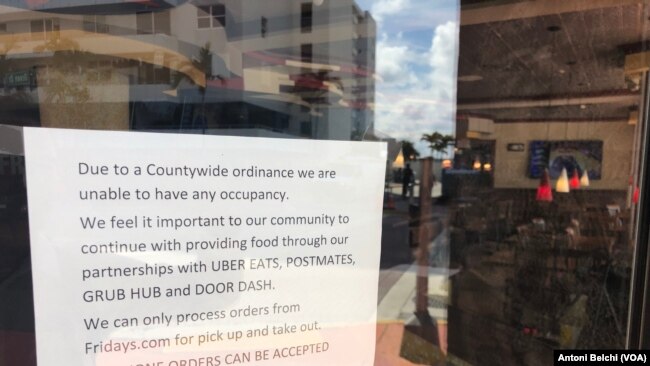 Un cartel en un restaurante de Miami Beach en el que se indica a los clientes que solo pueden atender pedidos de comida para llevar y entregas a domicilio, una de las medidas adoptadas por las autoridades para frenar el COVID-19.