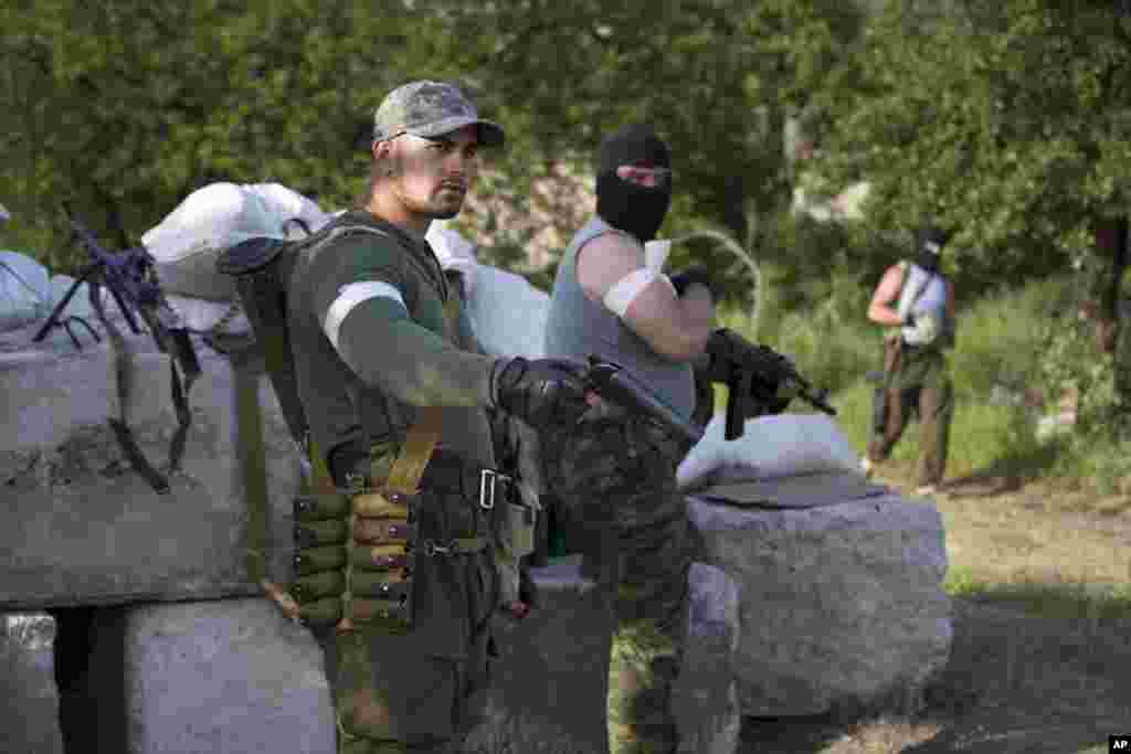 Armed Pro-Russian men prepare themselves to confront Ukrainian government troops at a checkpoint outside Slovyansk, eastern Ukraine, May 15, 2014. 
