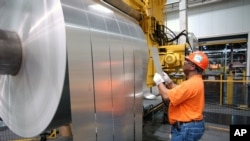 FILE - An Alcoa Warrick Operations employee inspects the finished rolls of aluminum as they come off the last stage of the production line in Indiana, April 7, 2006.