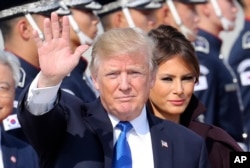 U.S. President Donald Trump waves as first lady Melania Trump, center right, stands upon their arrival at Osan Air Base in Pyeongtaek, South Korea, Tuesday, Nov. 7, 2017.