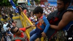 Un niño pasa la valla en la frontera mexicana mientras cientos de migrantes hondureños intenta cruzar la frontera hacia México, en Tecun Uman, Guatemala,