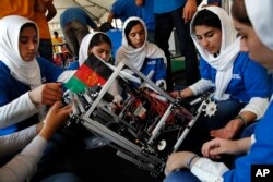 Lida Azizi, right, and other members of the Afghanistan team make a repair to their robot after their first round competing in the FIRST Global Robotics Challenge in Washington, July 17, 2017.