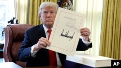 FILE - President Donald Trump displays the $1.5 trillion tax overhaul package he had just signed, Dec. 22, 2017.