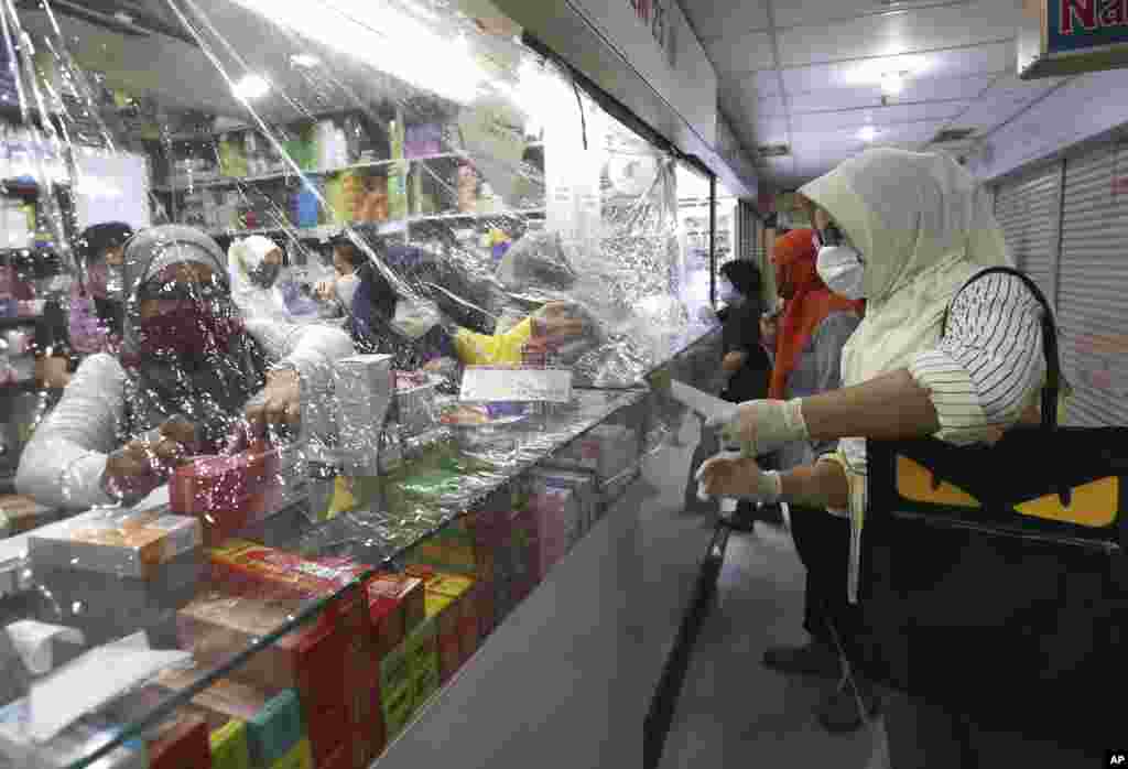 ترس از شیوع ویروس کرونا باعث نصب یک ورقه پلاستیکی بین کارکنان و مشتریان این فروشگاه در جاکارتا، اندونزی شده است.