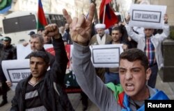 FILE - People gesture during a rally in support of Azerbaijan over the conflict in the breakaway Nagorno-Karabakh region, outside the Armenian Embassy in Kiev, Ukraine, April 8, 2016.