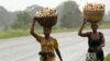 Women carry maize retrieved from fields flooded in the aftermath of Cyclone Kenneth, along the Mieze river near Pemba, Mozambique, April 30, 2019