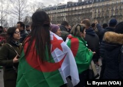 Women at a Paris protest are seen with the Algerian flag draped over their shoulders.
