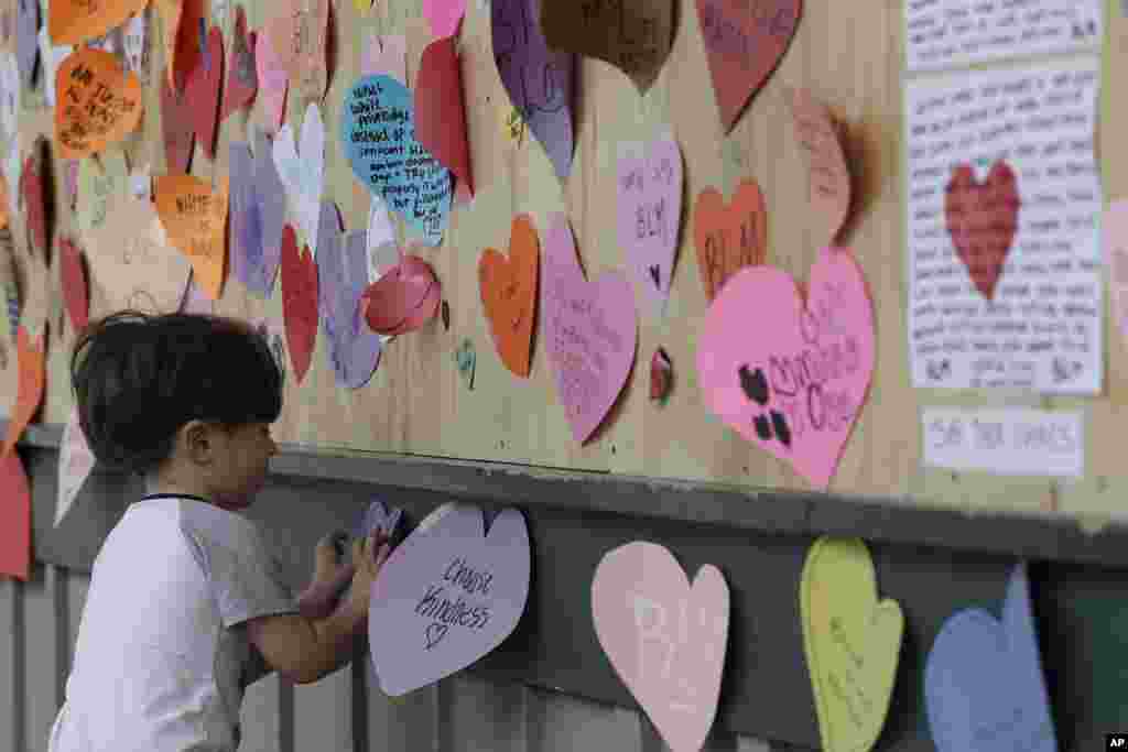 Two-year-old Jonah Pawola puts up a message outside Anderson&#39;s Bookshop in Naperville, Illinois Naperville locals are using the heart-shaped paper messages to show they support peace and will not accept hate and racism. (AP Photo/Nam Y. Huh)
