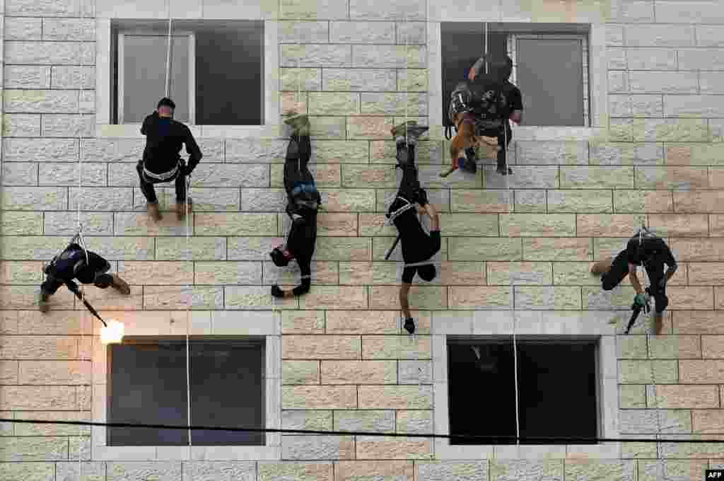 Palestinian members of Hamas&#39; security forces rappel along the wall of a building as they show off their skills during a police graduation ceremony in Gaza City.