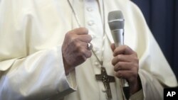 El papa Francisco cierra el puño al responder preguntas de periodistas durante una conferencia de prensa a bordo del vuelo a Roma al finalizar su vistia de dos días a Irlanda el domingo 26 de agosto de 2018. (AP Foto/Gregorio Borgia, Pool)