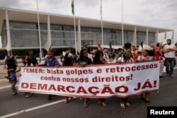 FILE - Indigenous people of the Guarani-Kaiowa tribe take part in a protest asking for the demarcation of their lands in Mato Grosso do Sul state, in front of Planalto Palace in Brasilia, Brazil, May 17, 2016.