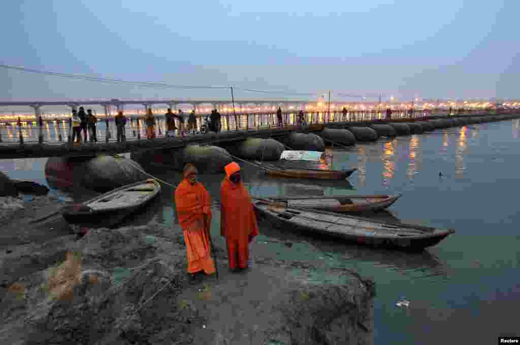 Sadhus - Hindu holy men - stand on the banks of river Ganges next to a pontoon bridge in the northern Indian city of Allahabad.