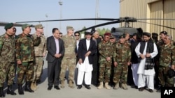 Afghanistan President Ashraf Ghani, center, poses with U.S. and local military officials during a ceremony after receiving two Black Hawk helicopters from the U.S. government, at Kandahar Air Field, Afghanistan, Oct. 7, 2017.
