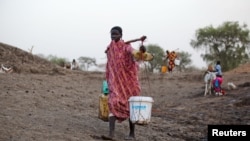 A woman carries water from a water hole near Jamam refugee camp in South Sudan's Upper Nile State, March 10, 2012.