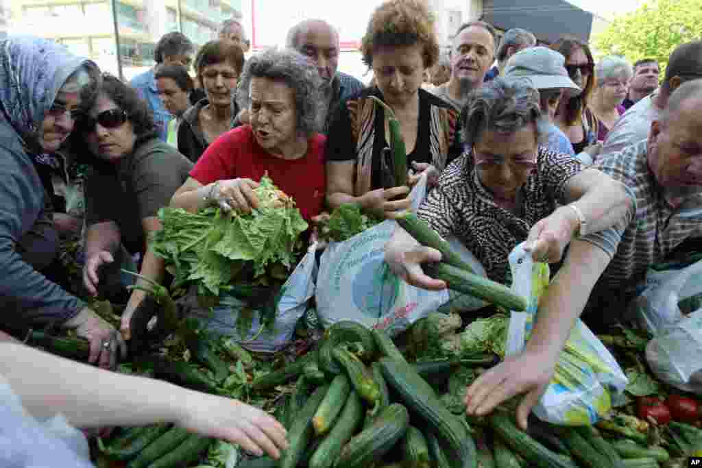 People reach out for fresh produce distributed by Greek fruit and vegetable street market vendors during a protest in Athens. The union of Greek farmers markets went on strike as protesters set up stands and started distributing vegetables to a fast growing crowd.