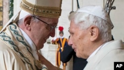 FILE - Pope Francis, left, and Pope Emeritus Benedict XVI hug at a Vatican ceremony, Dec. 8, 2015. Benedict shares his thoughts on the papacy in a new book, 'The Last Conversations.'