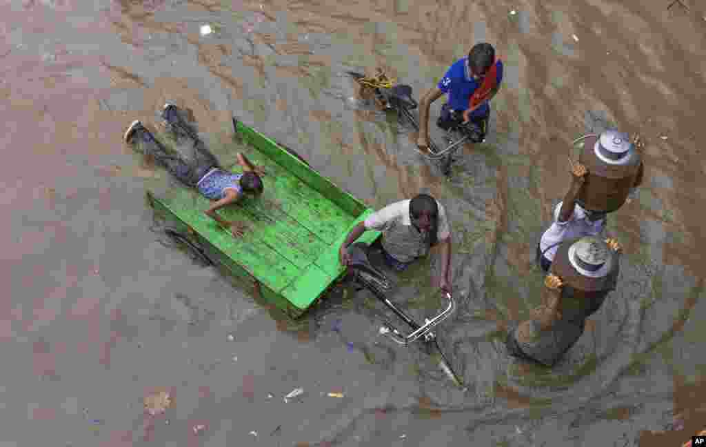Indian milkmen make their way through a water logged street following heavy rains in Allahabad.