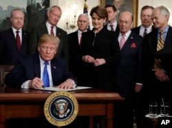 President Donald Trump signs a presidential memorandum imposing tariffs and investment restrictions on China in the Diplomatic Reception Room of the White House, March 22, 2018.