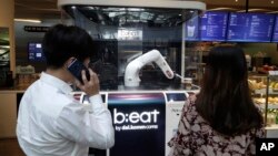 In this May 22, 2019, photo, customers wait for coffees in front of a robot named b;eat after placing an order at a cafe in Seoul, South Korea. (AP Photo/Lee Jin-man)