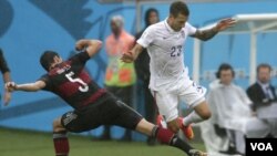ນັກເຕະບານເຢຍຣະມັນ Mats Hummels (ຊ້າຍ) ແລະ ນັກຫຼິ້ນສະຫະລັດ Fabian Johnson ກຳລັງຍາດບານກັນ