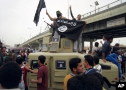 FILE - Islamic State militants hold up their flag as they patrol in a commandeered Iraqi military vehicle in Fallujah, Iraq, March 30, 2014. The terror group found a foothold in Somalia in October 2015, and is working to build up its presence there.