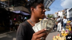 Un joven muestra sus billetes de un dólar en un mercado callejero en Caracas, Venezuela, el 11 de junio de 2021.