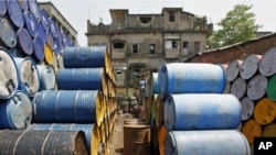 A labourer works amid oil containers at a wholesale fuel market in Kolkata, India, April 7, 2011.