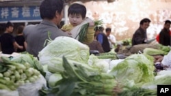 A vegetable vendor carries his child at a stall in Beijing. China's consumer prices rose 5.4 percent over a year ago, driven by 11.7 percent surge in food costs, Apr 16, 2011