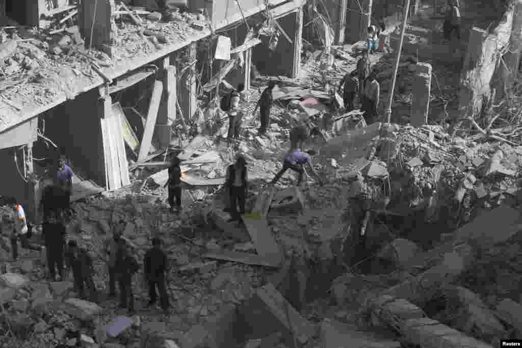 Residents inspect a damaged site after what activists say were four air strikes by forces loyal to Syria's President Bashar al-Assad in Douma, eastern al-Ghouta, near Damascus, Sept. 24, 2014.