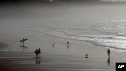 FILE - People walk on the beach of Biarritz, southwestern France, along the Atlantic Ocean, Dec. 18, 2015. New research shows the oceans are storing much more heat than previously thought.