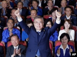 South Korea's presidential candidate Moon Jae-in of the Democratic Party raises his hands as his party leaders and members watch on television local media's results of exit polls for the presidential election in Seoul, South Korea, May 9, 2017.