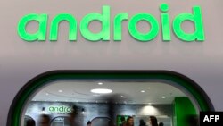 FILE - In this Feb. 25, 2019, photo, visitors walk past the Android stand at the Mobile World Congress (MWC) in Barcelona.