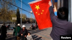 FILE - A Chinese national flag is raised outside a residential building in Lhasa.